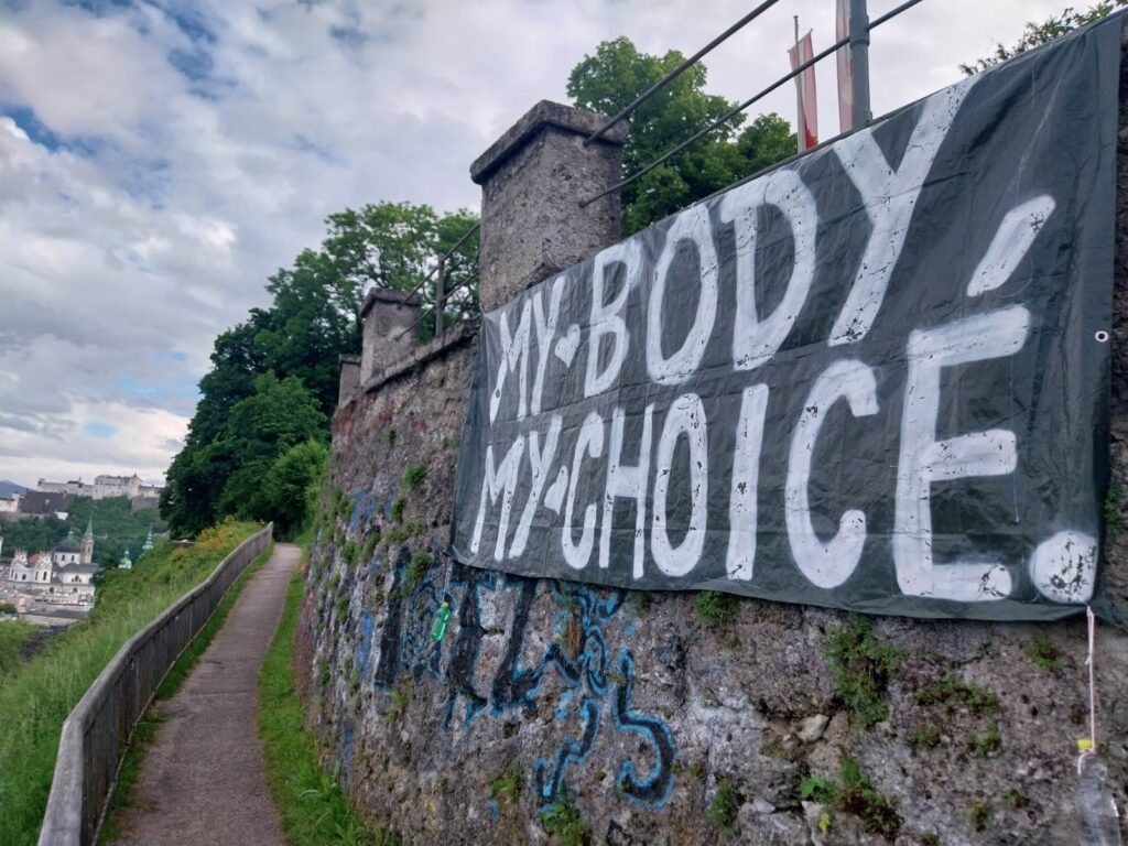 Privire spre fortăreața Hohensalzburg. În prim-plan se vede un banner cu inscripția: My Body, my Choice (Corpul meu, alegerea mea).